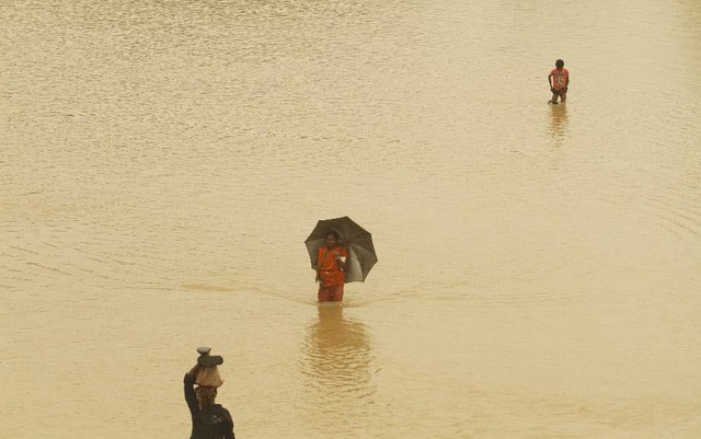 Người dân lội qua đường ngập lụt sau nhiều ngày mưa lớn tại huyện Kendrapara, bang Orissa, Ấn Độ.