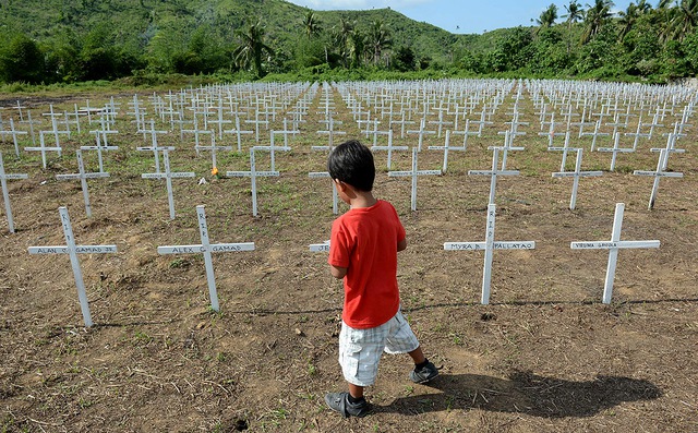 Cậu bé đi qua mộ tập thể của hàng nghìn nạn nhân thiệt mạng trong siêu bão Haiyan vào năm 2013 ở thành phố Tacloban, Philippines.