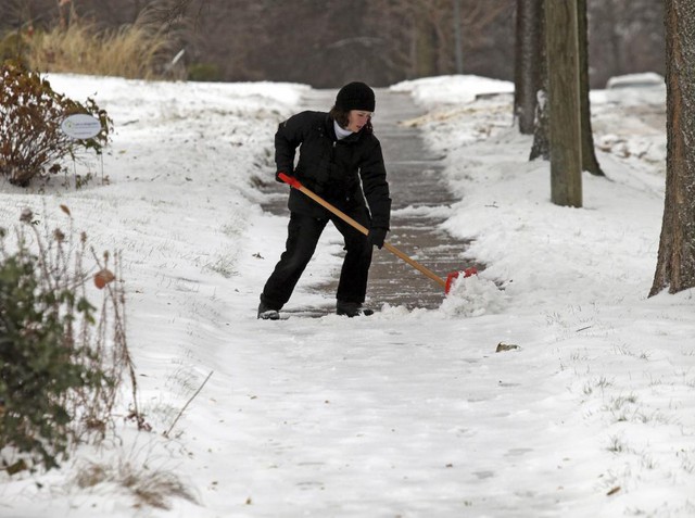 Một phụ nữ dọn tuyết rơi phủ kín đường ở Minneapolis, Mỹ.