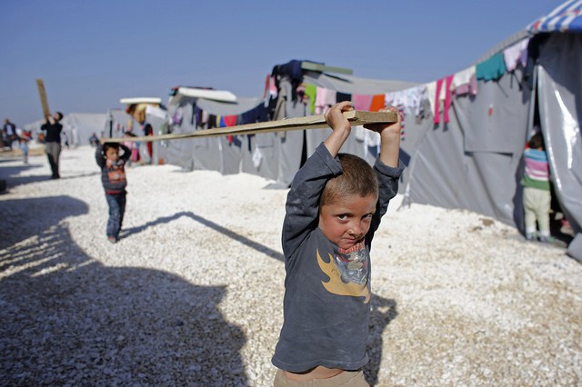 Trẻ em tị nạn người Kurd, đến từ thị trấn Kobani ở Syria, vác một thanh gỗ trong trại tị nạn tại thị trấn Suruç, Thổ Nhĩ Kỳ.