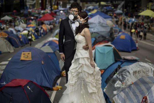 Cặp đôi đeo mặt nạ, chụp ảnh cưới giữa những lều bạt của người biểu tình trên đường phố ở Hong Kong.