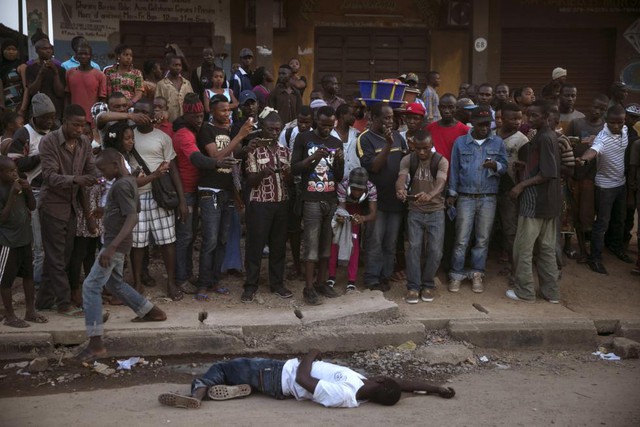 Người qua đường vây quanh thi thể của người bị nghi tử vong do nhiễm Ebola ở Koidu, Đông Sierra Leone.