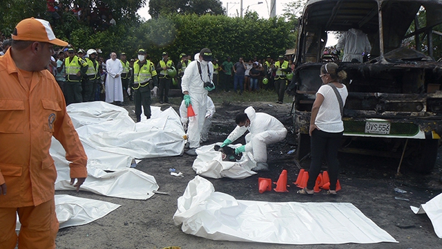 Cảnh sát đứng cạnh các thi thể trẻ em thiệt mạng trong vụ cháy xe bus ở Fundacion, Colombia.