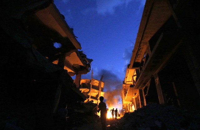 Người dân Palestine đốt lửa để thắp sáng trong đêm tối tại khu dân cư bị phá hủy trong cuộc không kích của quân đội Israel nhằm vào thành phố Gaza.