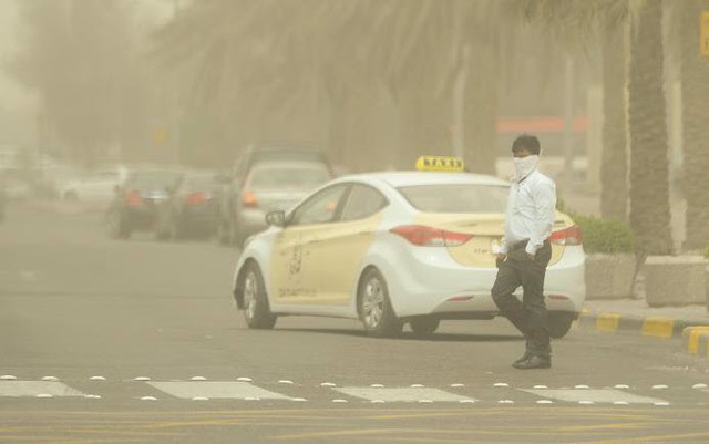 Một người đàn ông dùng khăn che mặt đi trên đường, khi bão cát tấn công thành phố Kuwait City, Kuwait.