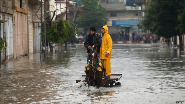 Hai người Palestine di chuyển bằng xe ngựa trên đường phố ngập lụt sau mưa lớn ở thành phố Gaza.