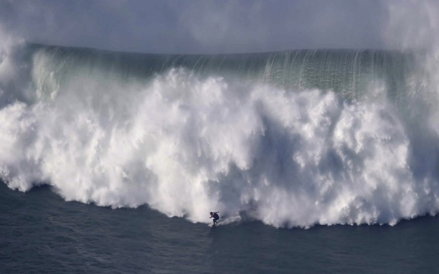 Người đàn ông lướt ván trước một con sóng khổng lồ ở ngoài khơi Praia do Norte ở Nazare, miền trung  Bồ Đào Nha.