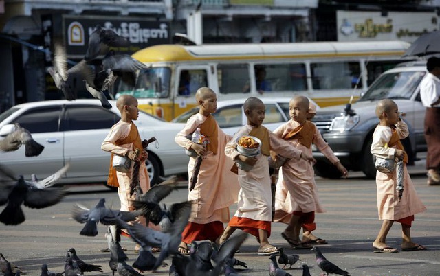 Sư tiểu đi khất thực trên đường gần chùa Sule ở thành phố Yangon, Myanmar.