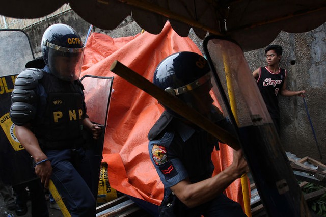 Cảnh sát vào một ngôi nhà trong chiến dịch giải tỏa khu ổ chuột tại thành phố Quezon, Philippines.