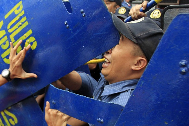 Người biểu tình đẩy khiên vào mắt một cảnh sát chống bạo động trong cuộc biểu tình yêu cầu quân đội Mỹ rút khỏi Philippines.