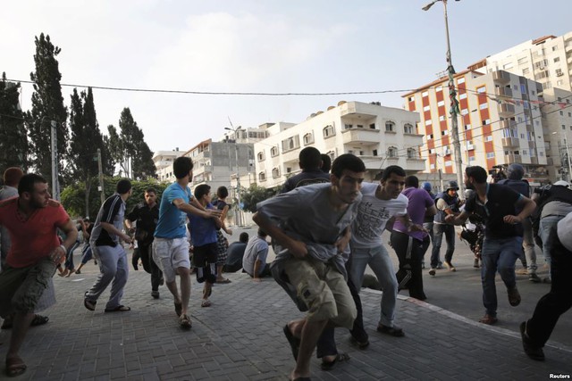 Người dân Palestine chạy tìm nơi trú ẩn khi máy bay chiến đấu Israel không kích gần thành phố Gaza.