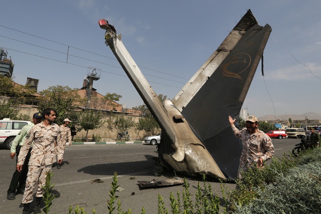 Các thành viên của Lực lượng vệ binh cách mạng Iran đứng bảo vệ xác của máy bay rơi gần sân bay Mehrabad  ở thủ đô Tehran. Tai nạn khiến ít nhất 45 người thiệt mạng.
