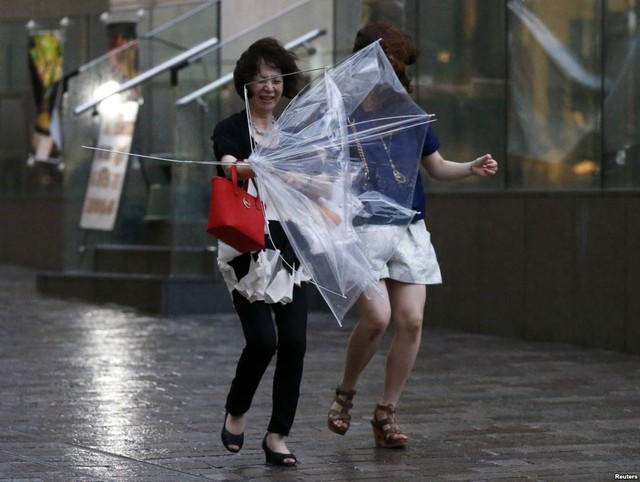 Những người phụ nữ vất vả chống chọi với gió lớn gây ra bởi cơn bão Halong ở Tokyo, Nhật Bản.
