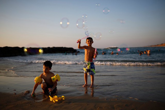 Trẻ em chơi thổi bong bóng trên bãi biển ở Ashkelon, Israel.