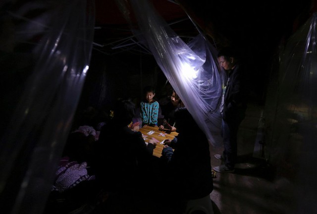 Một gia đình chơi bài trong lều tạm sau trận động đất ở Vân Nam, Trung Quốc.