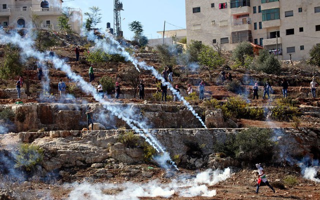 Người biểu tình Palestine chạy khỏi đạn hơi cay do quân đội Israel bắn ra trong cuộc đụng độ bên ngoài nhà tù quân sự Ofer gần thành phố Ramallah, Bờ Tây.