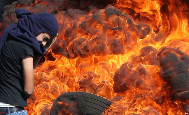 Người biểu tình Palestine dùng tay che mặt, đứng trước đống lốp xe đang cháy dữ dội trong cuộc đụng độ với cảnh sát Israel tại thành phố Nablus, Bờ Tây.