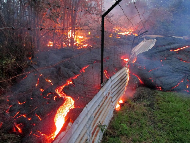 Nham thạch nóng phun trào từ núi lửa chảy qua hàng rào ở Pahoa, Hawaii, Mỹ.