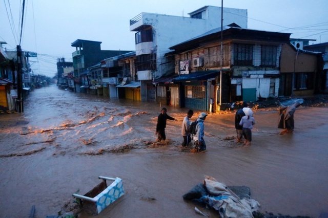 Người dân đi trên đường phố ngập lụt sau khi siêu bão Hagupit quét qua thành phố Borongan, Philippines.