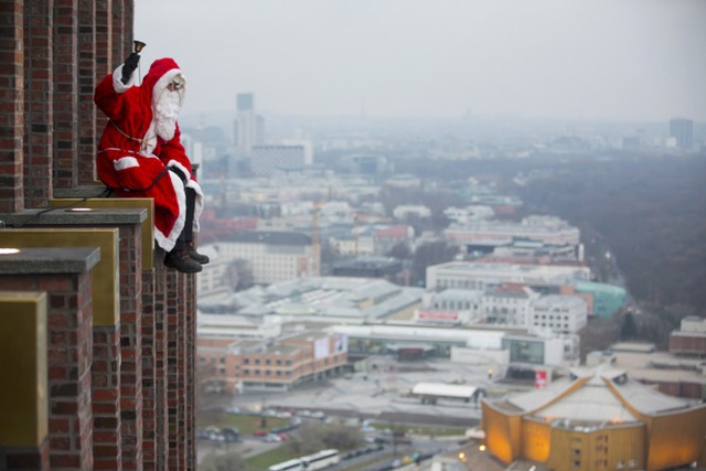 Người đàn ông mặc trang phục ông già Noel ngồi trên đỉnh ngọn tháp Kollhoff  tại quảng trường Potsdamer Platz  ở Berlin, Đức.
