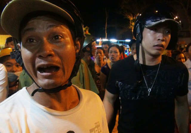 Ông Trịnh Văn Khén (trái) bức xúc la hét phản đối nhân viên gánh xiếc buộc ông phải mua vé mới được vào đón con