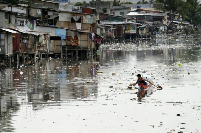 Người đàn ông chèo thuyền trên dòng sông ô nhiễm ở Paranaque, Philippines.