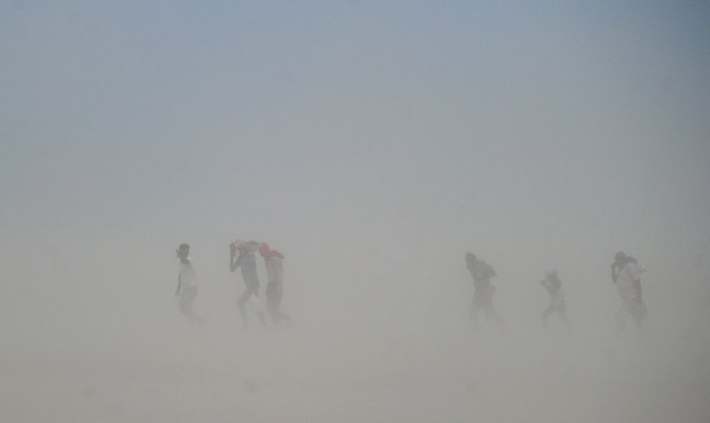 Người dân đi trong bão cát dọc bờ sông Hằng ở Yamuna, Ấn Độ.