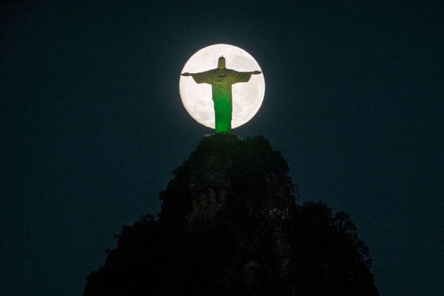 Mặt trăng đang lặn sau tượng chúa Redeemer trên đỉnh núi Corcovado ở Rio de Janeiro, Brazil.