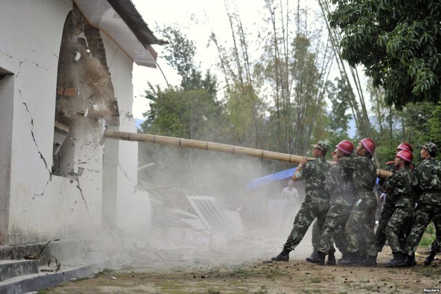 Cảnh sát bán quân sự Trung Quốc phá hủy một ngôi nhà sau trận động đất mạnh 5,6 độ richter tại huyện Doanh Giang, tỉnh Vân Nam, Trung Quốc.