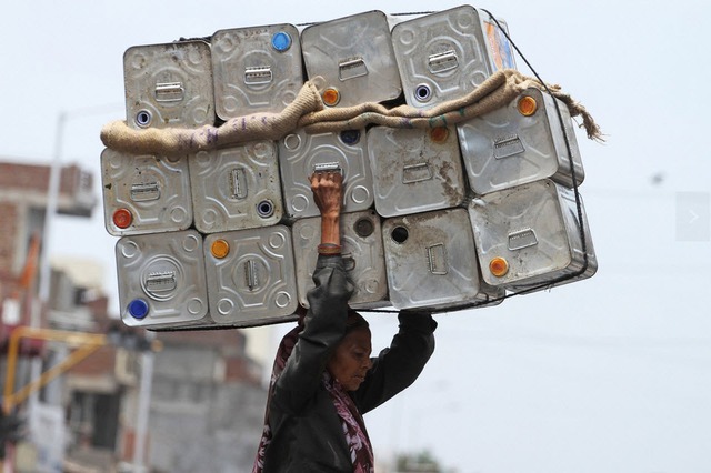 Một phụ nữ vác vỏ thùng dầu tới một điểm thu mua đồ tái chế ở Ấn Độ.