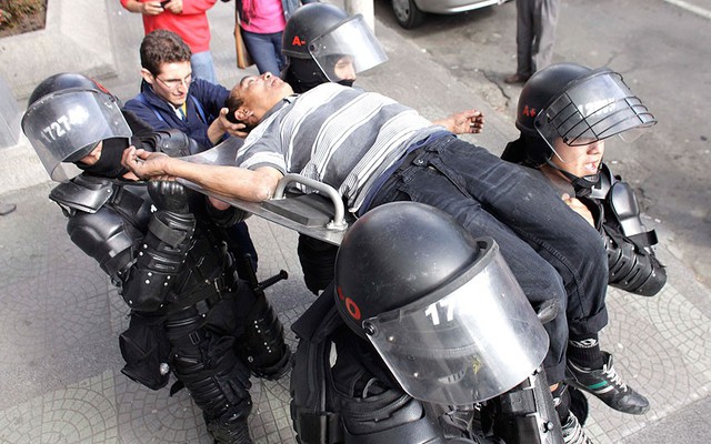 Cảnh sát chống bạo động khiêng một người ngất xỉu do bị xịt hơi cay trong cuộc biểu tình ở Colombia.