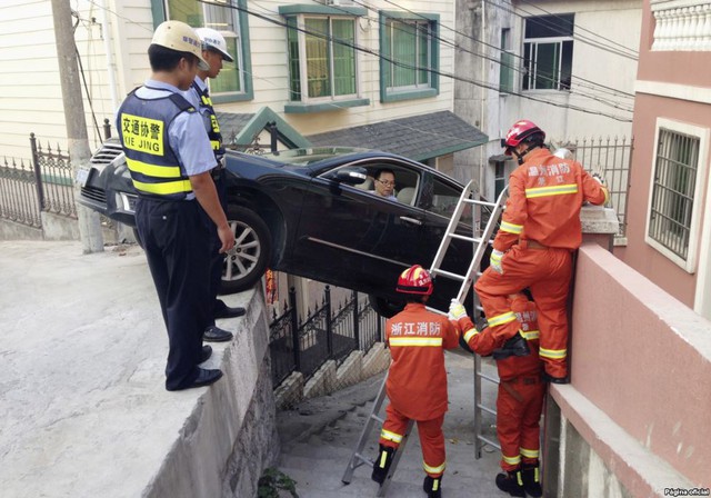 Các nhân viên cứu hộ giúp đỡ đưa tài xế khỏi chiếc xe ô tô mắc kẹt trên một ngõ nhỏ ở thành phố Ôn Châu, Trung Quốc.