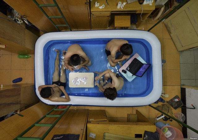 Các sinh viên ngồi trong bể tắm bơm hơi để tránh nóng tại khu ký túc xá ở thành phố Vũ Hán, Trung Quốc.