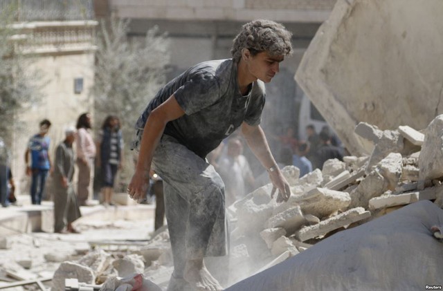 Người đàn ông tìm kiếm nạn nhân sống sót trong đống đổ nát của tòa nhà bị sập sau vụ ném bom của quân đội chính phủ tại tỉnh Idlib, Syria.
