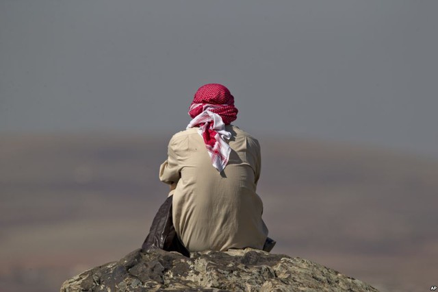 Người đàn ông ngồi quan sát chiến sự tại thị trấn Kobani ở Syria, từ đỉnh ngọn đồi tại thị trấn Suruc, Thổ Nhĩ Kỳ.
