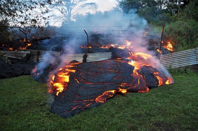 Nham thạch núi lửa chảy qua một hàng rào tại thị trấn Pahoa, Hawaii.