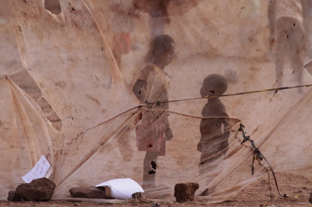 Trẻ em chơi gần màn chống muỗi được sử dụng làm lưới sau gôn bóng đá ở Lusaka, Zambia.