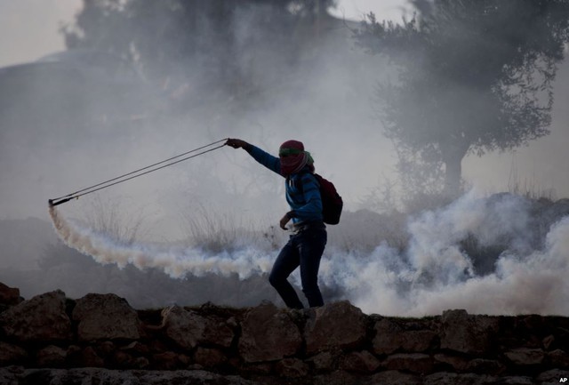 Người biểu tình Palestine dùng súng cao du để nắm lựu đạn hơi cay trở lại phía cảnh sát Israel trong cuộc đụng độ gần thành phố Ramallah, Bờ Tây.