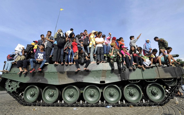 Khách tham quan đứng, ngồi trên xe tăng tại triển lãm quân sự Alutsista trong công viên Monas, Jakarta , Indonesia.