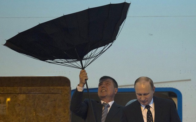 Nhân viên an ninh vất vả với chiếc ô bị gió thổi lật, khi Tổng thống Nga Vladimir Putin xuống máy bay để tới tham dự hội nghị thượng đỉnh về hợp tác và niềm tin ở châu Á lần thứ tư (CICA-4) tại Thượng Hải, Trung Quốc.