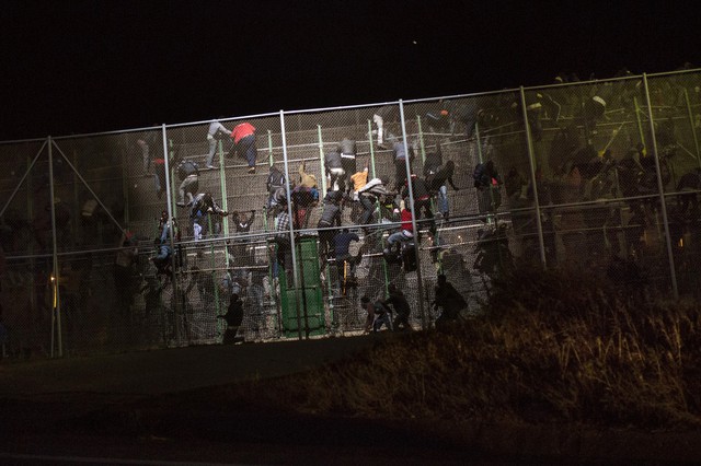 Những người di cư ở Tiểu vùng Saharan trèo lên hàng rào sắt phân chia biên giới giữa Ma-rốc và Tây Ban Nha để vượt biên.