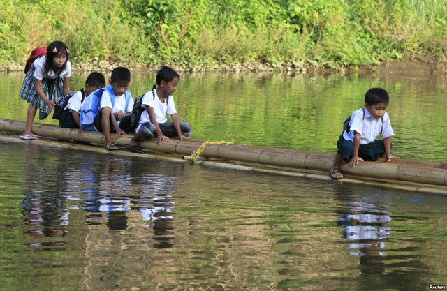 Học sinh Tiểu học ngồi trên bè tre vượt sông tới trường ở huyện Rodriguez, tỉnh Rizal, Philippines.