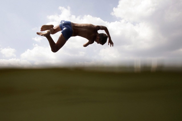 Một cậu bé nhảy xuống dòng kênh tắm mát dưới trời nắng nóng ở Minsk, Belarus.