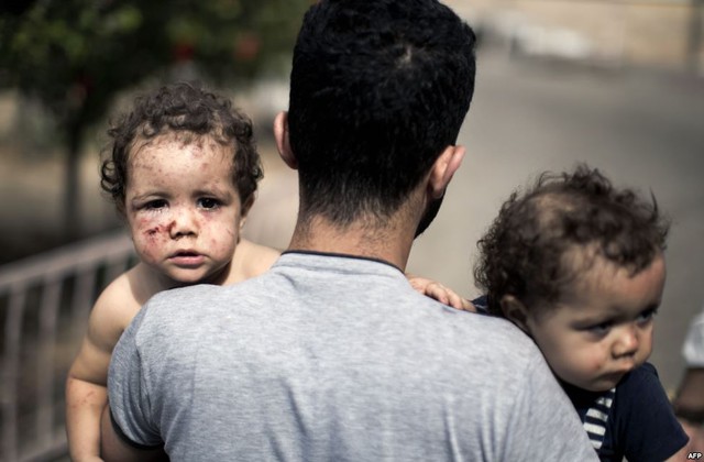 Một người đàn ông Palestine bế hai con gái trong một tấn công bằng xe tăng của Israel tại thành phố Gaza.