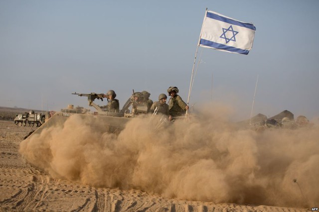 Các binh sĩ Israel ngồi trên một chiếc xe bọc thép chở quân đang hướng tới thành phố Gaza.