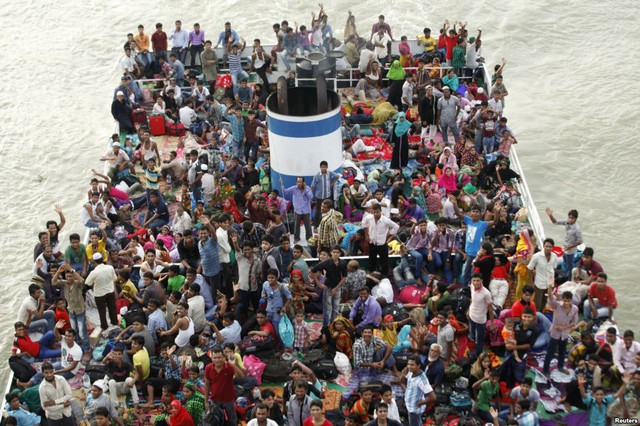 Mọi người ngồi kín mặt boong một chiếc tàu quá tải đang di chuyển trên sông Buriganga ở Dhaka, Bangladesh.