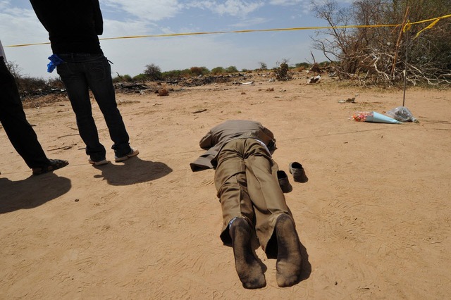 Người đàn ông nằm cầu nguyện cho thân nhân thiệt mạng trong vụ máy bay AH5017 rơi, tại hiện trường ở vùng Gossi, Mali.