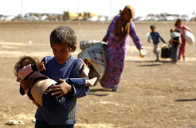 Một cậu bé tị nạn người Syria bế em nhỏ sau khi vượt qua biên giới sang Thổ Nhĩ Kỳ tại thị trấn Suruc, tỉnh Sanliurfa.