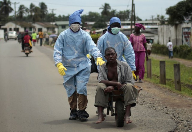 Người dân mặc đồ bảo hộ y tế đưa một người đàn ông nghi nhiễm virus Ebola tới bệnh viện Island ở Monrovia, Liberia.