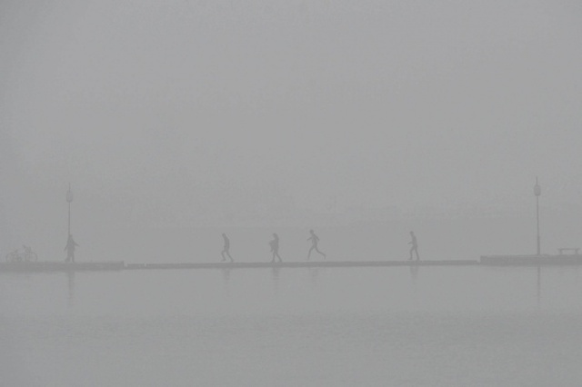 Mọi người đi qua cây cầu bao phủ bởi màn sương mù dày ở thành phố Tương Dương, Trung Quốc.
